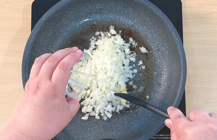 フライパンにたまねぎ、しょうが、にんにくを入れて弱火～中火で炒める様子