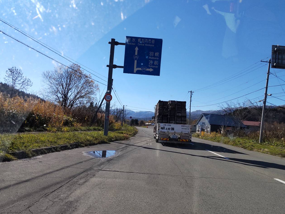 北海道の道を走る西澤養蜂場の車の写真