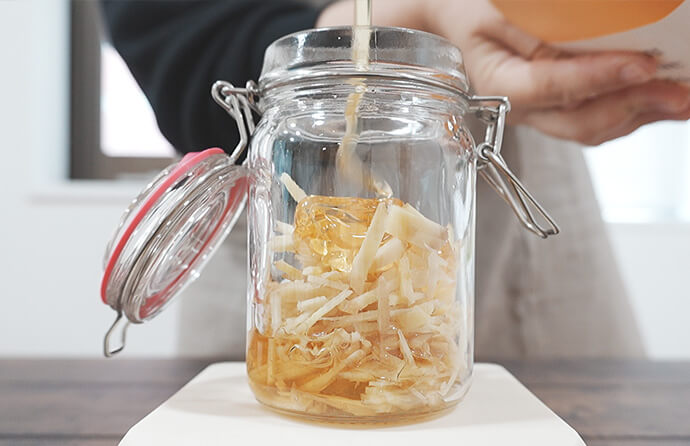 瓶にしょうがとはちみつを入れる様子